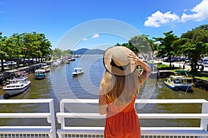 Tropical Holidays. Beautiful woman holding hat enjoying tropical landscape