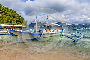Tropical island landscape with bangca traditional philippines boats anchored at the shore, Palawan