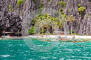 Tropical island landscape with bangca traditional philippines boats anchored at the shore, Palawan