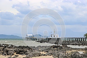 Tropical island - sand and stones on the shore and a religious Buddhist building on the pier. Koh Phayam Island, Thailand