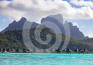 Tropical landscape - huts on piles, the sea and mountains