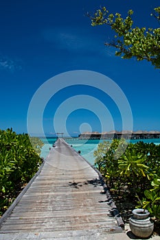 Tropical landscape with wooden bridge and water villas at Maldives