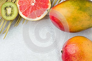 Tropical Nature Background Ripe Juicy Red Mango Slices of Grapefruit Kiwi Spiky Green Yellowish Palm Leaf. Healthy Food Lifestyle