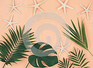 Tropical palm leaves on pastel coral orange background. Trendy tropical pattern. Flat lay. Summer, vacation, holidays concept