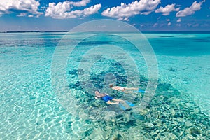 Tropical paradise beach. Caucasian couple of tourists snorkel in crystal turquoise water near Maldives Islan