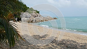 Tropical Paradise exotic white sand beach washed by blue calm sea. Sandy shore with green coconut palms under cloudy sky