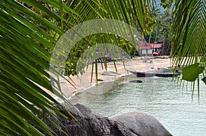 Tropical paradise - sandy beach and longtail boat behing rocks a