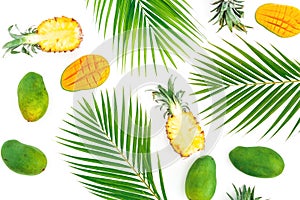 Tropical pattern of pineapple and mango fruits with palm leaves on white background. Flat lay, top view.