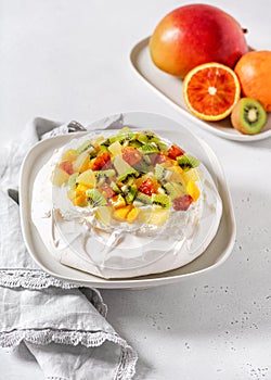 Tropical Pavlova meringue cake with kiwi, mango, pineapple, blood orange slices and whipped cream.
