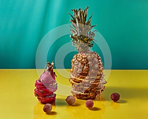 Tropical Pineapple fruit single whole and dragon fruit, pitaya made up of sliceson and litchi fruits on a duotone yellow