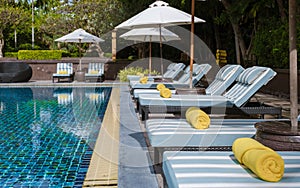 tropical pool with palm trees and beach bed chairs, beach chairs with beach towel at a pool