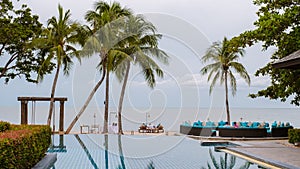 tropical pool with palm trees and beach bed chairs, beach chairs with beach towel at a pool