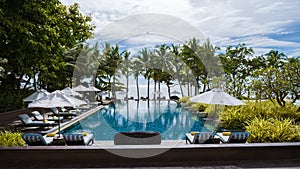 tropical pool with palm trees and beach bed chairs, beach chairs with beach towel at a pool