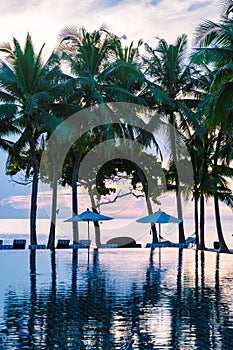 tropical pool with palm trees and beach bed chairs, beach chairs with beach towel at a pool