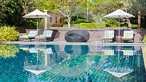 tropical pool with palm trees and beach bed chairs, beach chairs with beach towel at a pool