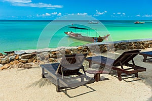 Tropical resort with chaise longs under palms on sandy beach