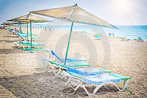 Tropical resort sea beach. Umbrellas and chaise lounges near sea on sandy beach. Relax and rest on beach