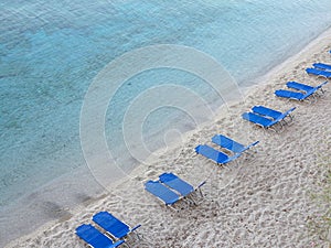 Tropical sand beach with blue empty deckchair