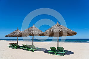 Tropical sand beach and summer sea water with blue sky and straw umbrella. Travel and nature concept