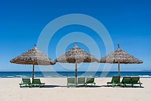 Tropical sand beach and summer sea water with blue sky and straw umbrella. Travel and nature concept