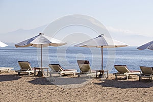 Tropical sand beach with sun loungers and umbrellas with a view of the volcano next to the sea water in island Bali, Indonesia