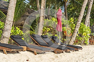 Tropical sand beach with wooden deck chairs and umbrellas near sea on a sunny day. Nature concept. Thailand