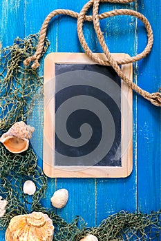 Tropical sea background. Different shells, old fishing net on the blue boards, top view. Free space for inscriptions on the slate