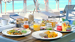 Tropical sea vacation in modern resort. Buffet breakfast in outdoor hotel restaurant with sea and sun lounge on