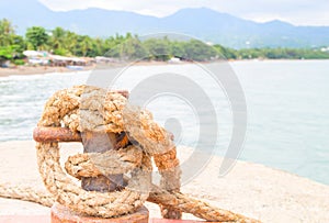 Tropical seaside landscape. Pier rope holder with rustic tackle closeup.