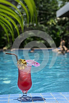 tropical sinagpore sling cocktail in tall glass by swimming pool