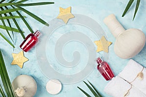 Tropical spa mockup: white towels, red shampoo bottles, Thai masage bags, golden stars and green fern leaves on blue background