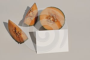 Tropical stationery mock-up. Blank greeting card, invitation. Fresh cut orange cantaloupe melon fruit with long harsh