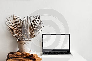 Tropical summer home office still life composition. Black laptop mockup with blank computer screen. Dry palm leaves in