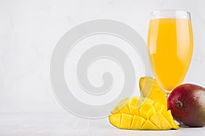 Tropical summer juice of ripe fresh mango with pulpy chopped slice on soft light elegant white background.