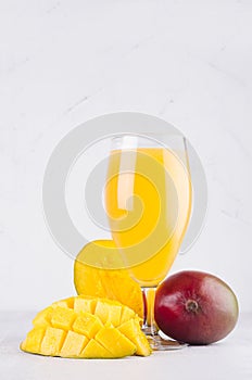 Tropical summer juice of ripe fresh mango with pulpy chopped slice on soft light elegant white background, vertical.