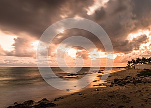 Tropical sunset with ocean and sand beach on foreground