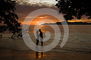 Tropical sunset, ocean shore with silhouette of a lover couple