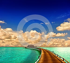 Tropical sunset seascape. overwater bungalow with jetty