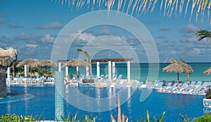 tropical swimming pool against tranquil ocean and cloudy blue sky on sunny day