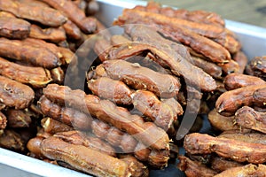 Tropical tamarind fruit without a shell, with visible seeds and inner pulp, in a galvanized tray on a wooden. Concept of food