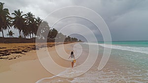 Tropical vacation on paradise island beach. Happy woman in dress enjoying sea sunrise. Dominican Republic