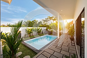 Tropical villa view with garden, swimming pool and open living room at sunrise