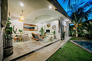 Tropical villa view with garden, swimming pool and open living room at sunset