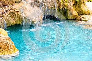 Tropical waterfall with emerald blue lake and rocks in jungle forest