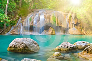 Tropical waterfall with emerald lake and rocks in jungle forest