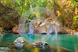 Tropical waterfall with emerald lake and rocks in jungle forest