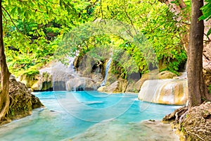 Tropical waterfall with emerald lake and rocks in jungle forest