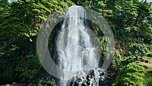 Tropical waterfall flowing down on sunny day. Mountain water stream falling