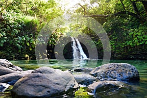 Tropical waterfall Lower Waikamoi Falls and a small crystal clear pond, inside of a dense tropical rainforest, off the Road to Han