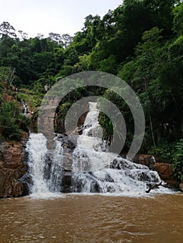 A tropical waterfall is raging tremendously feeding a small lake underneath